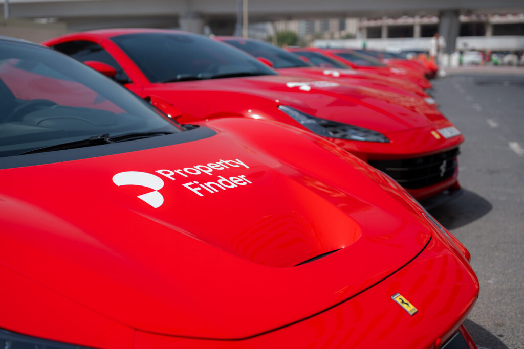 Close-up of red Ferrari sports cars branded with the Crypto Property Finder logo, lined up in Dubai for a SuperAgent recognition event.